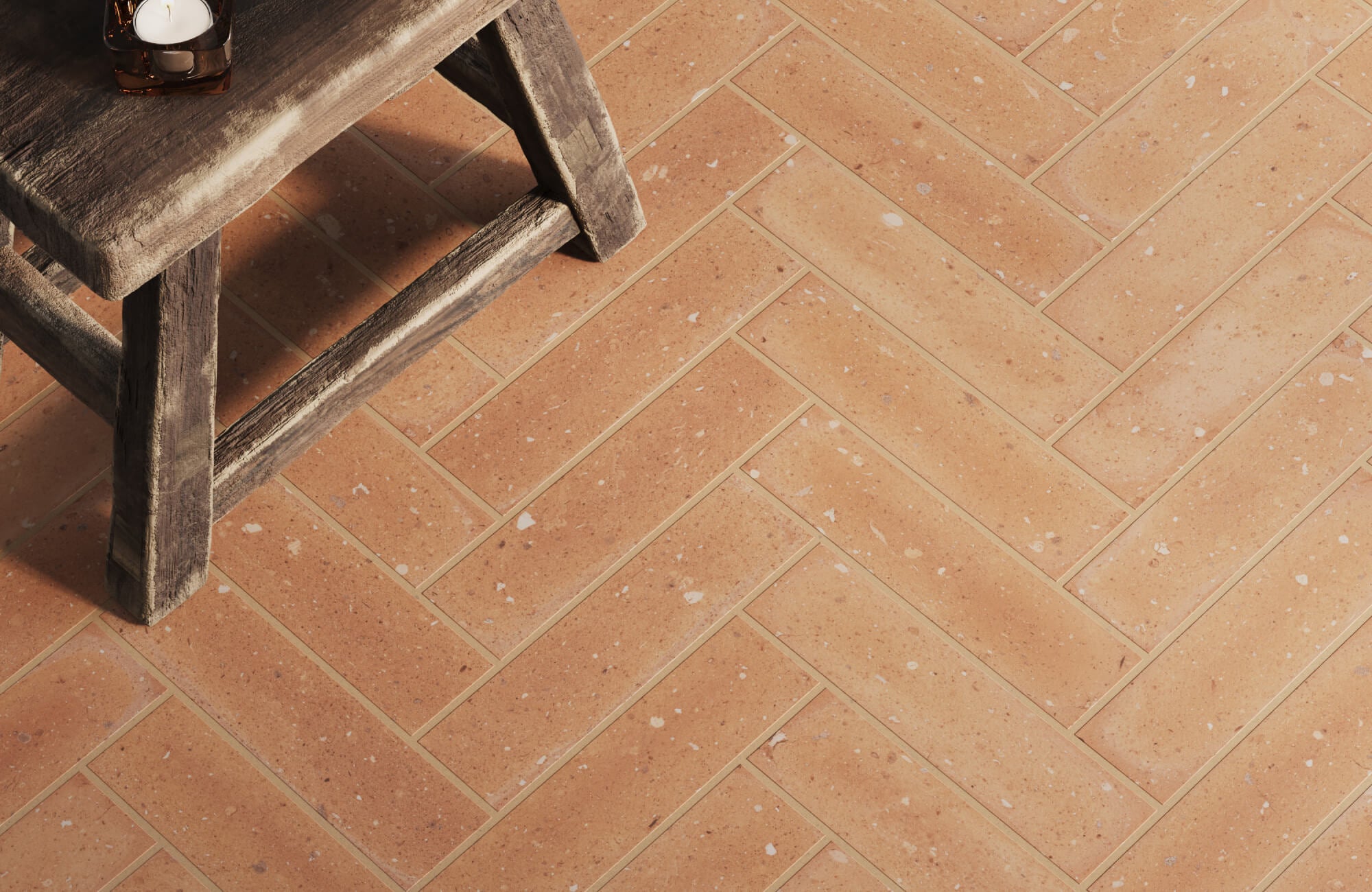 Warm-toned terracotta tiles arranged in a herringbone pattern, adding a rustic charm to the space. The earthy tones blend with the natural wood stool for a cozy aesthetic.