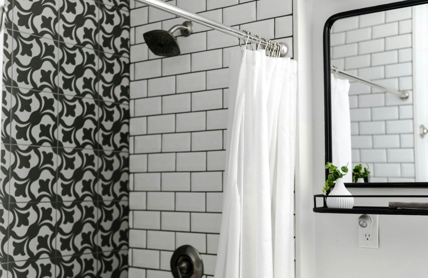 Bold floral-patterned tiles in rich black and white add dramatic contrast to this modern shower space, paired with classic white subway tiles with black grout for a sleek, cohesive look.