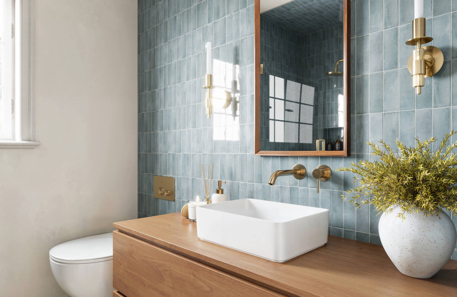 Modern bathroom featuring soft blue subway tiles, a wooden vanity with a white vessel sink, and gold fixtures for an elegant touch.