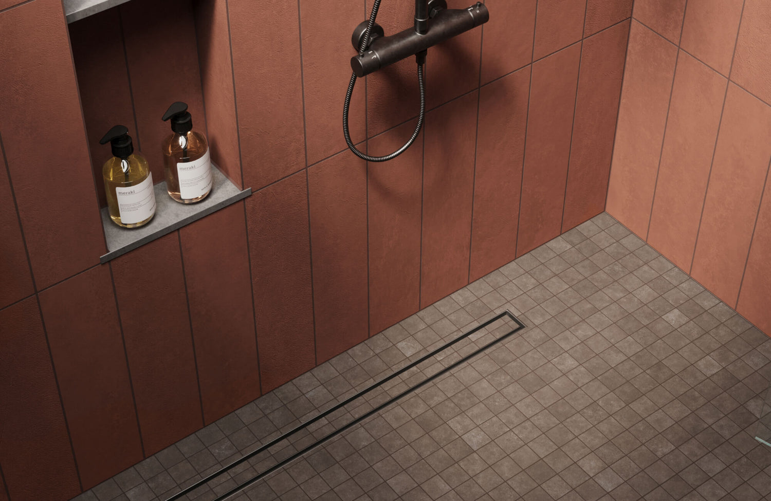 Modern shower space featuring earthy red wall tiles paired with muted brown mosaic floor tiles, accented by a sleek black shower fixture and minimalist recessed shelf holding bath products.