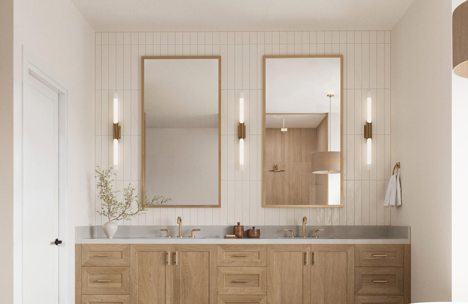 Double vanity bathroom with light wood cabinetry, tall mirrors, and vertical subway tiles creating a serene, modern aesthetic. Accented with brass fixtures and soft lighting for a warm, inviting feel.