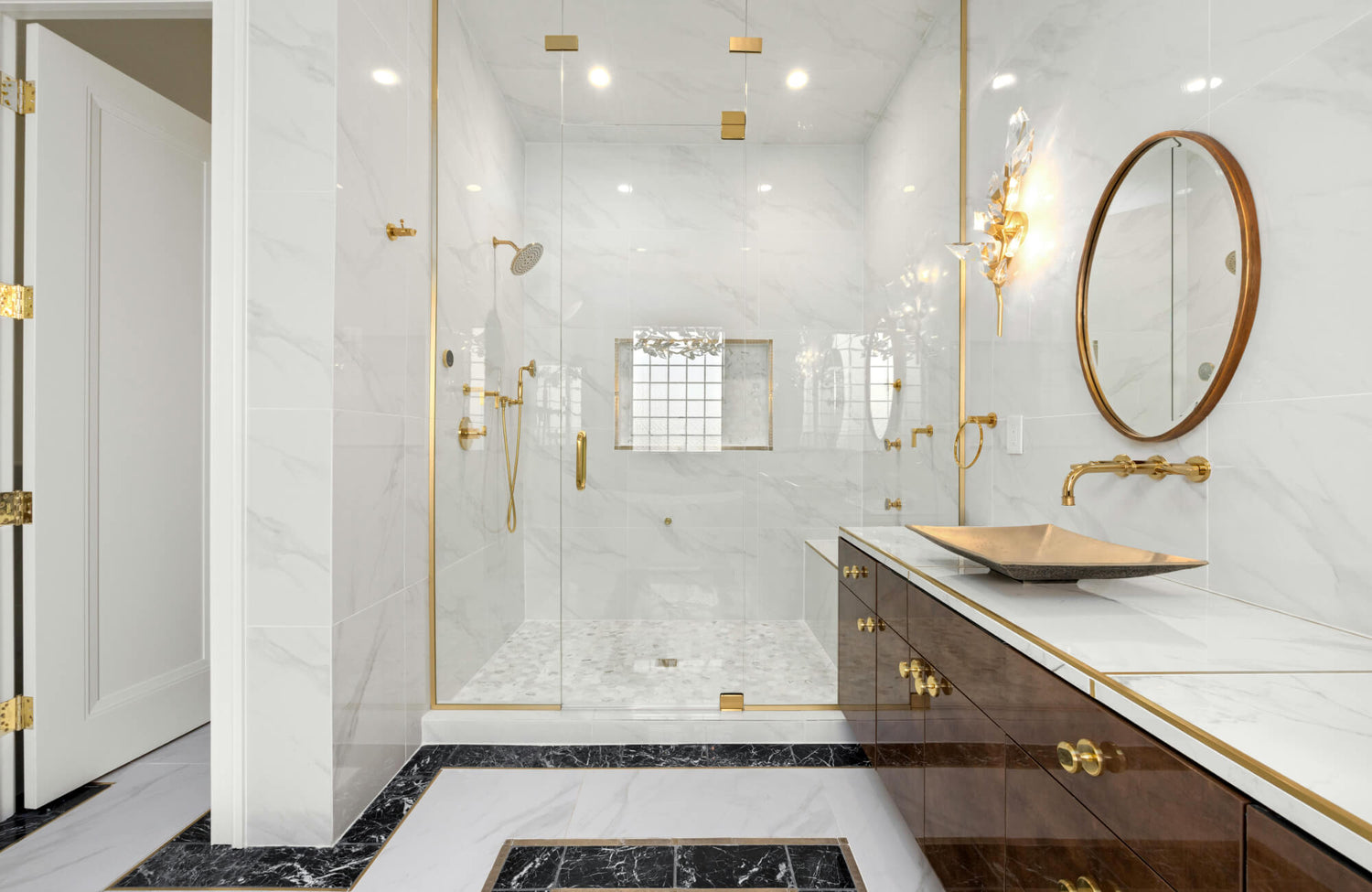 Luxurious bathroom featuring a Carrara marble shower with gold accents, a matching vanity, and elegant black marble trim.