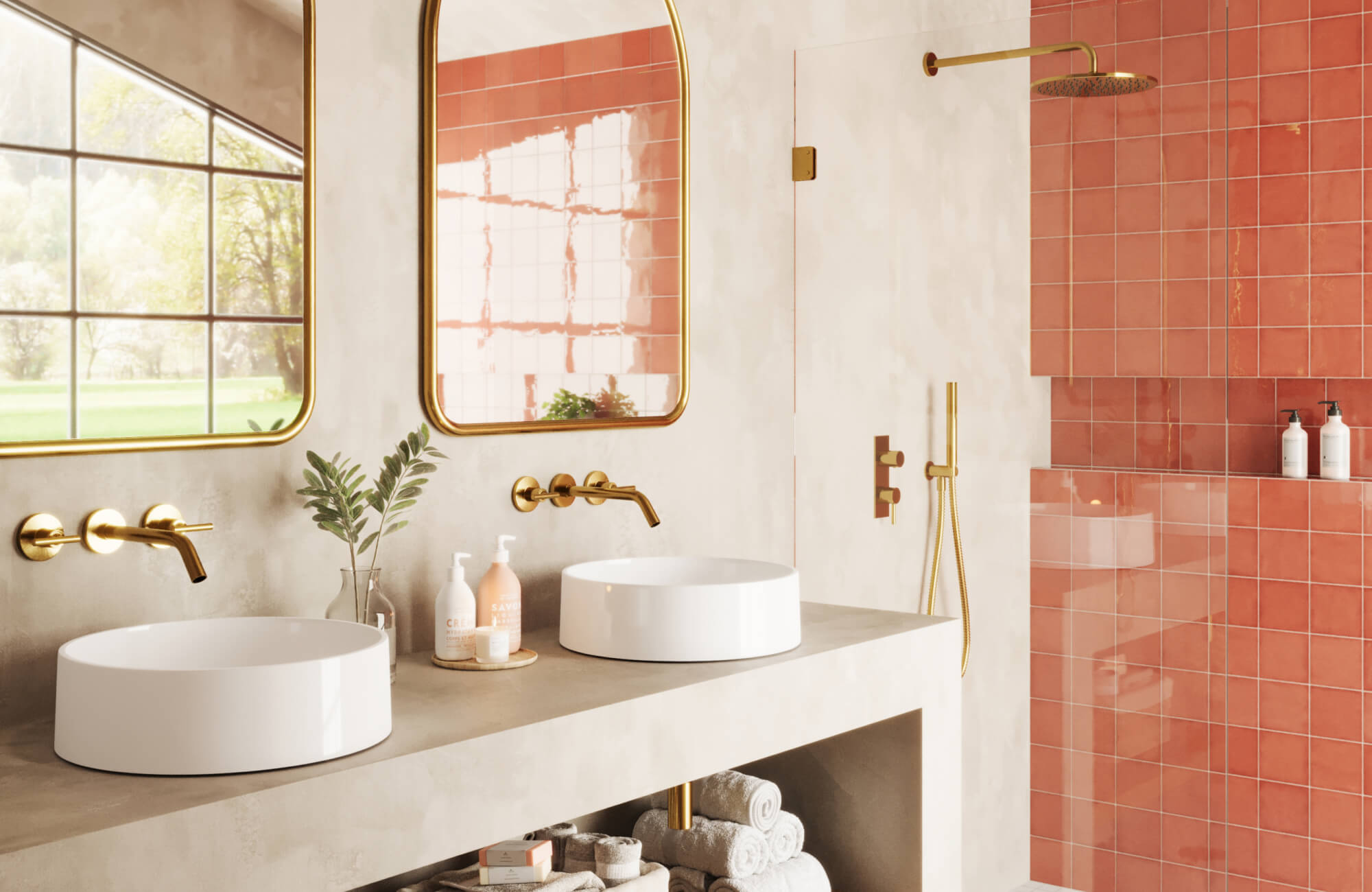 A modern bathroom with a soft beige vanity, gold fixtures, and bold coral tiles in the shower area. Twin round vessel sinks sit below large gold-framed mirrors, adding a luxurious touch.