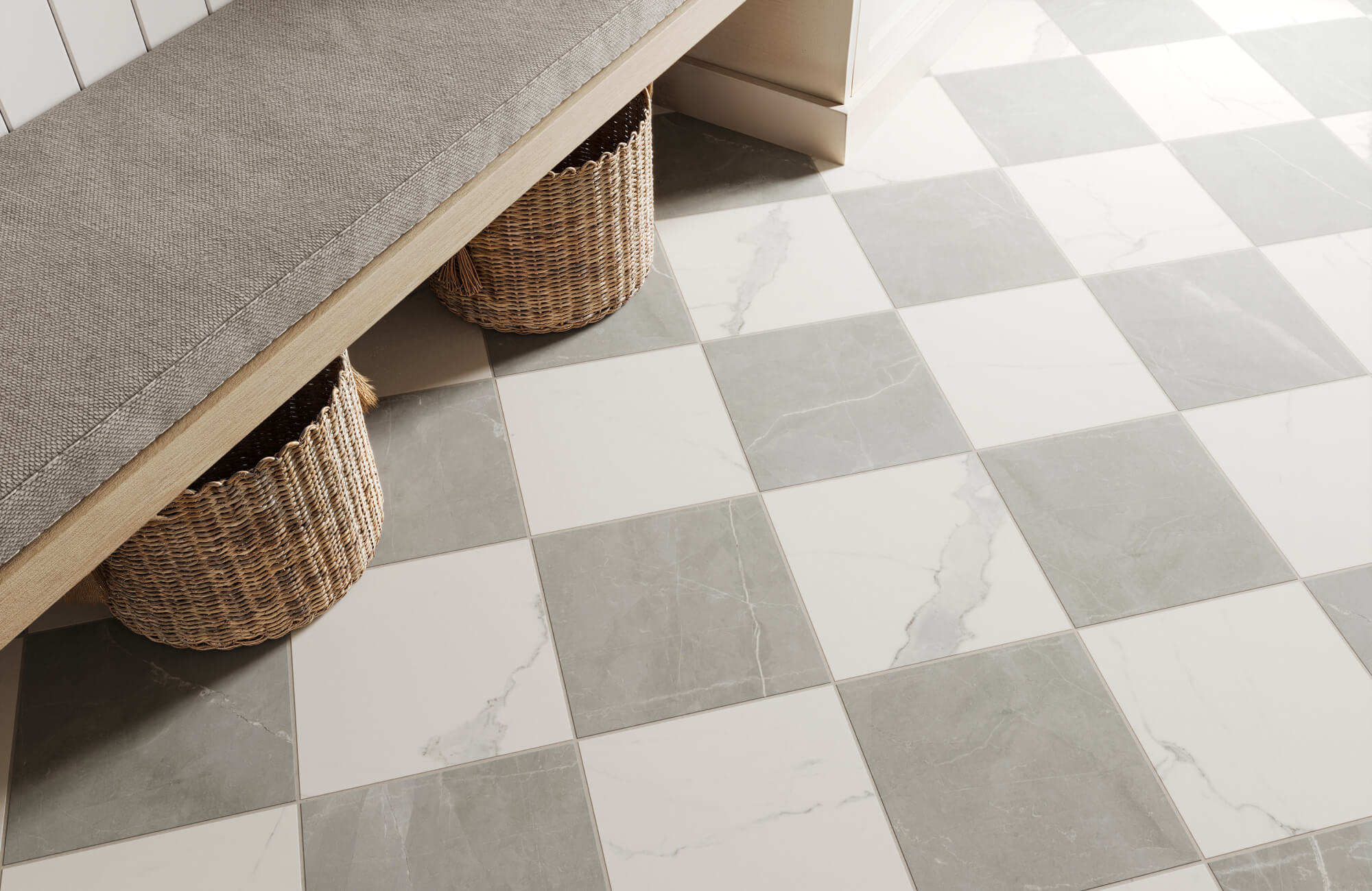 Close-up of soft grey and white checkerboard tiles under a bench with woven baskets, adding a cozy, organized touch to the mudroom.