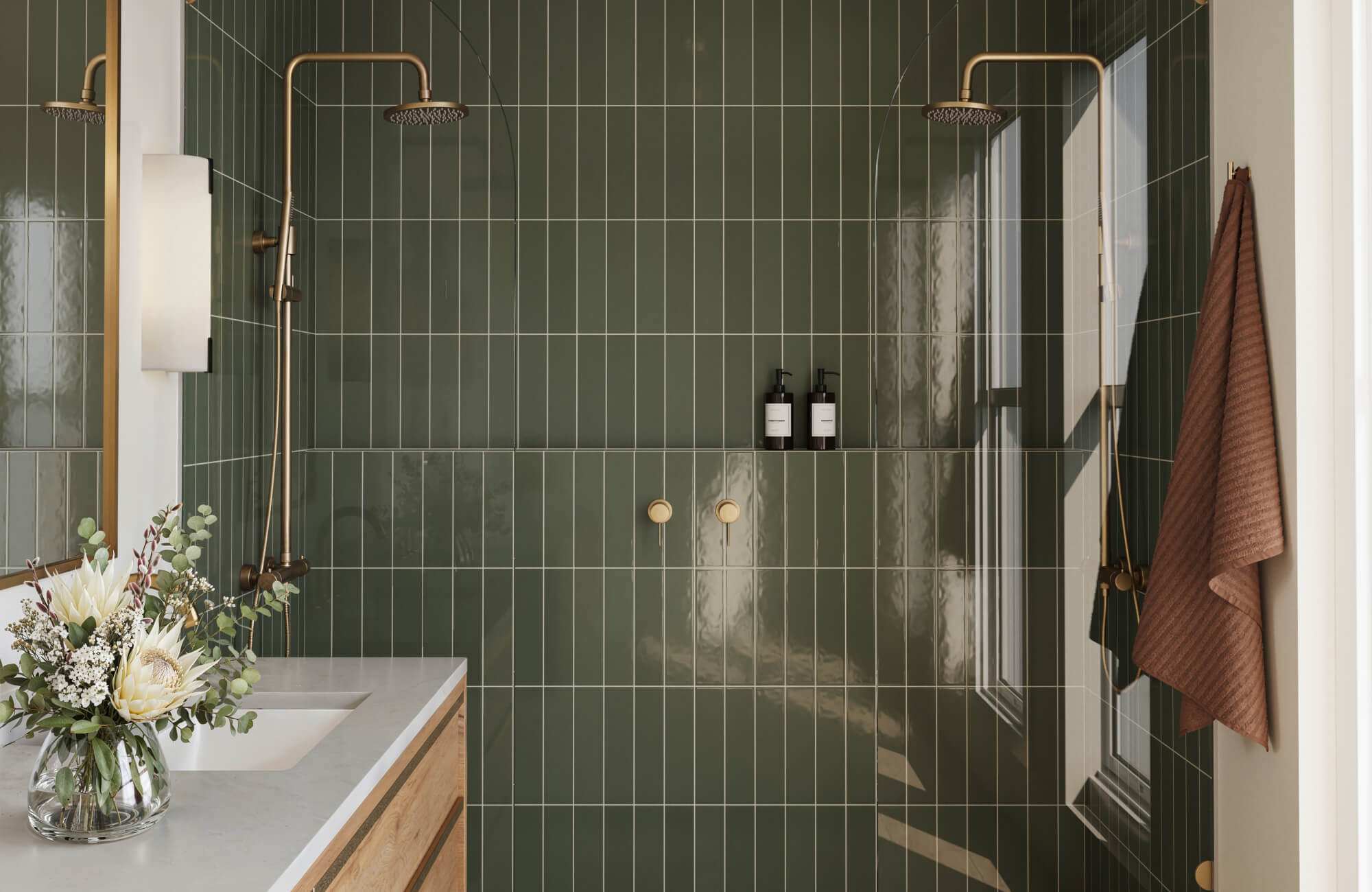 Stylish bathroom with glossy green vertical subway tiles, brass rainfall showerheads, and a modern vanity, creating a serene and luxurious spa-like atmosphere.