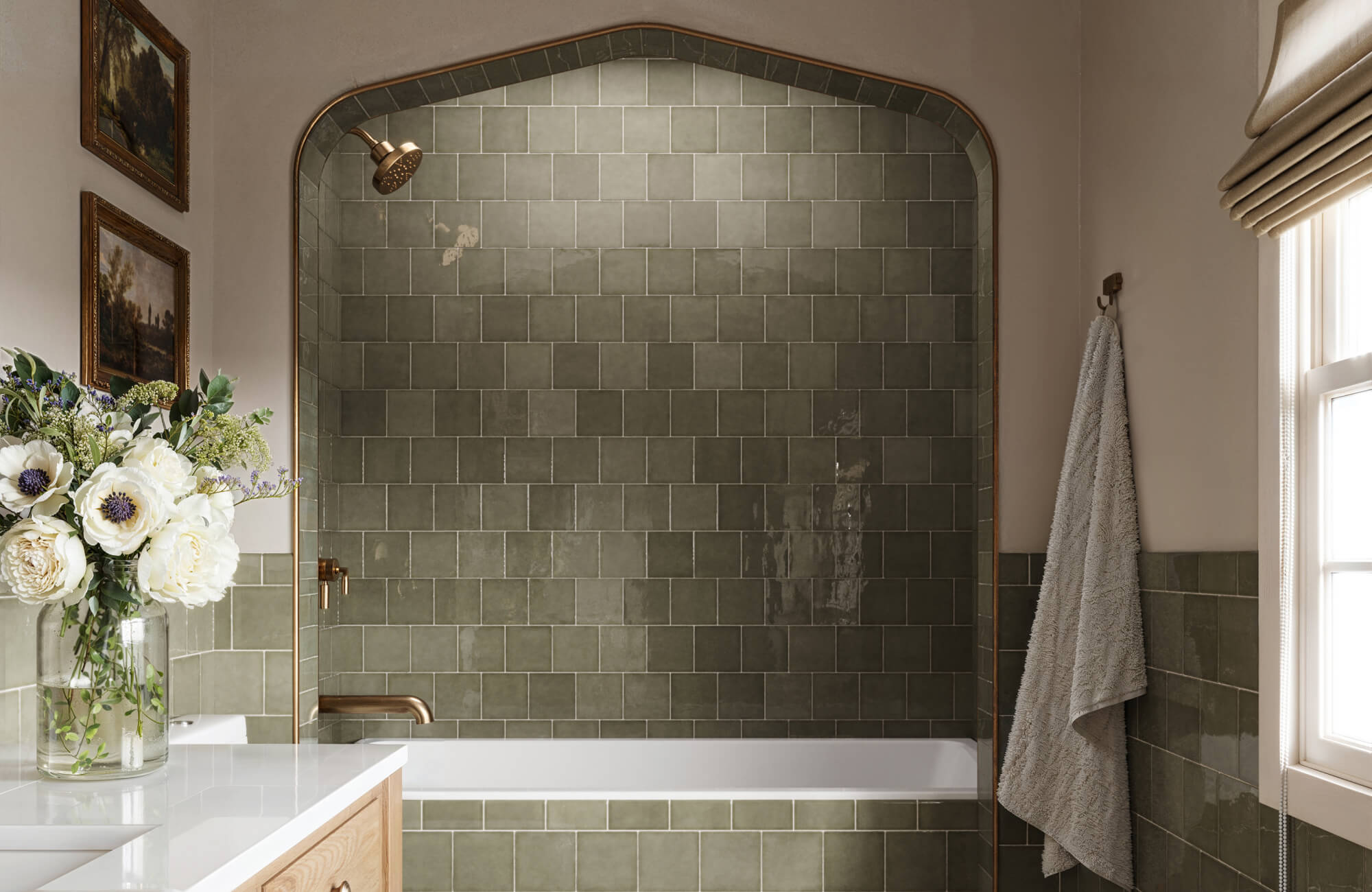 Elegant olive-green tiles envelop a cozy shower area with arched details, complemented by gold fixtures and natural light for a serene, timeless atmosphere.