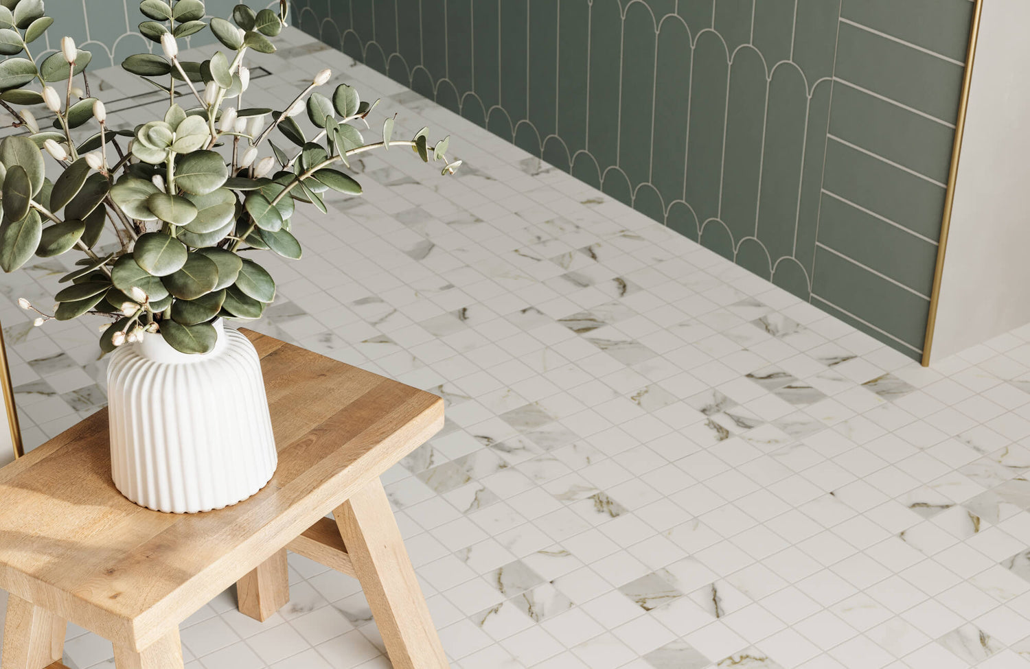 Light wood stool with a vase of greenery on white marbled bathroom floor tiles, paired with dark green wall tiles.