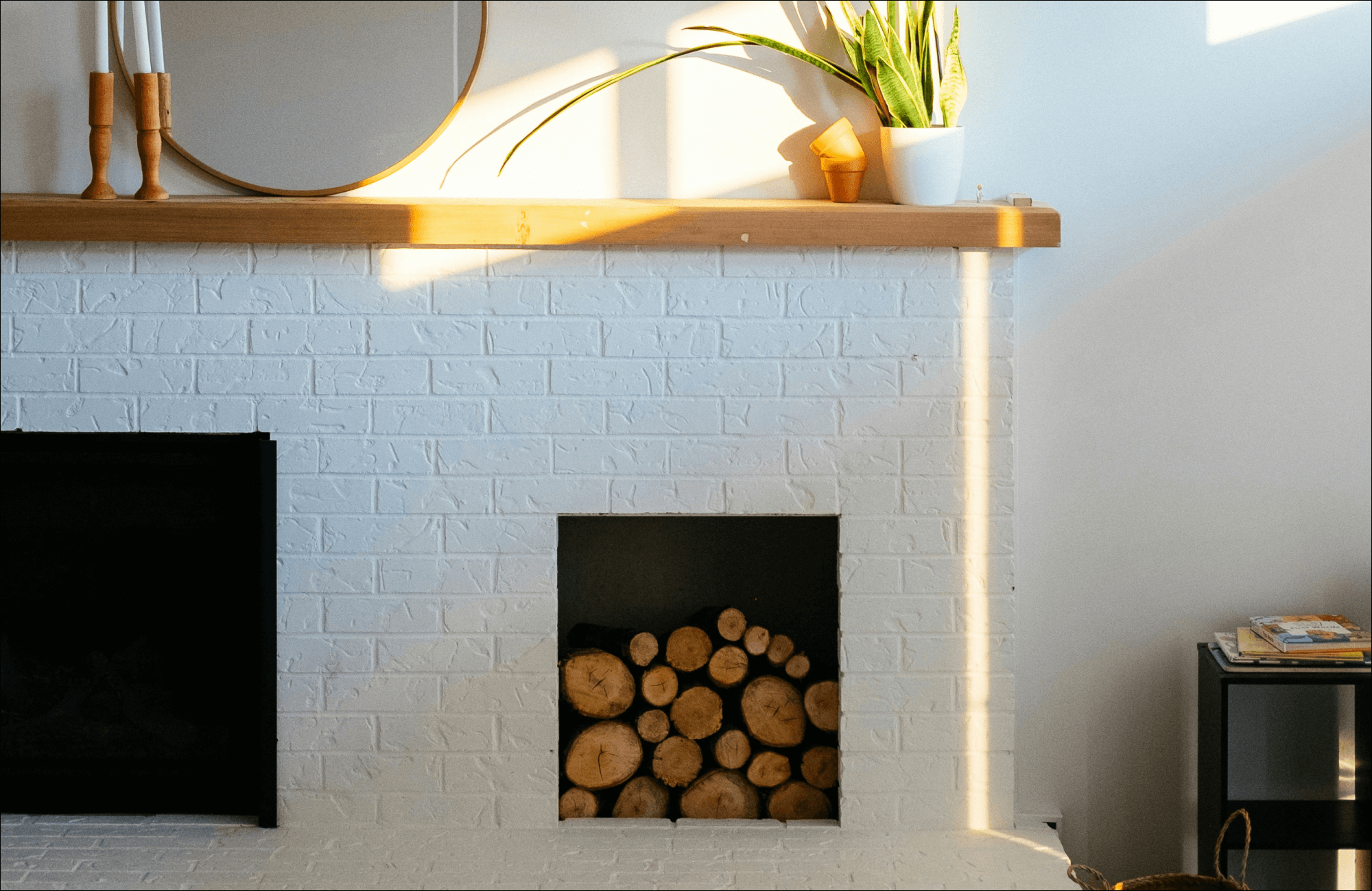 Neatly stacked firewood inside a white brick fireplace creates a rustic yet cozy aesthetic, blending natural elements with modern simplicity.