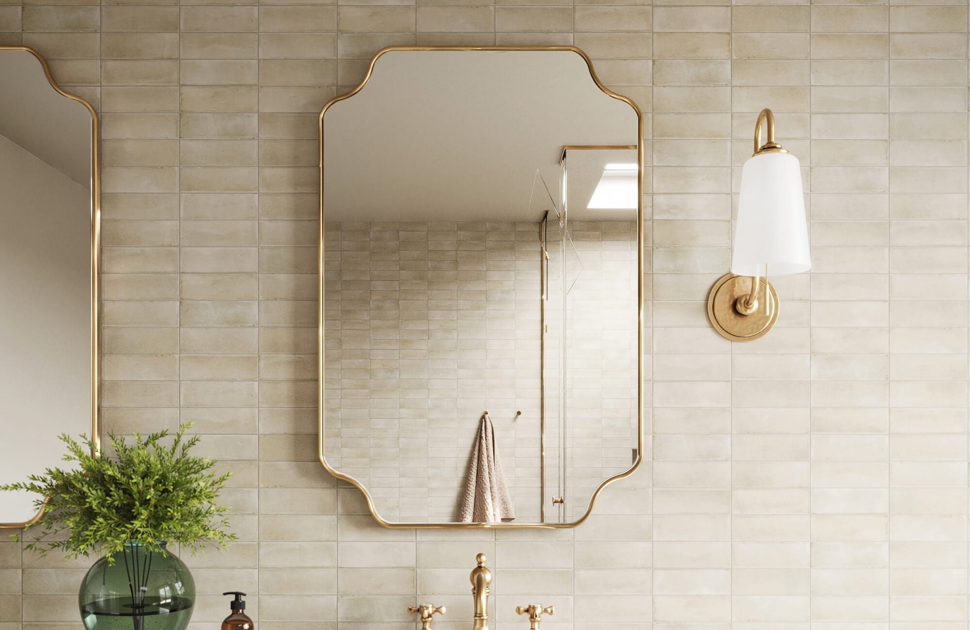 Elegant bathroom with soft beige subway tiles, gold-framed mirrors, brass fixtures, and a timeless wall sconce.