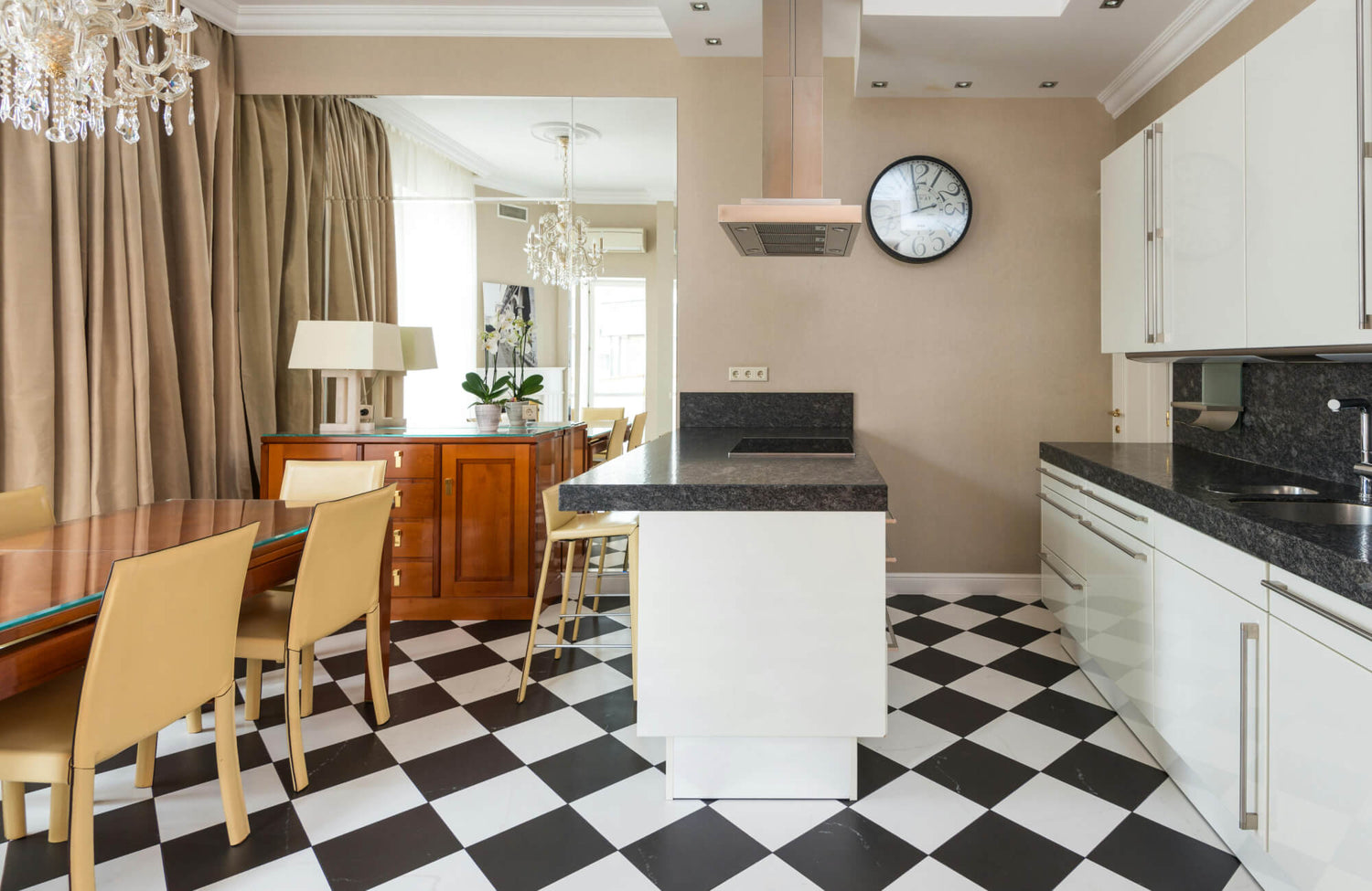 Elegant kitchen and dining area featuring classic black and white checkerboard flooring, contrasting with warm beige and wooden accents.