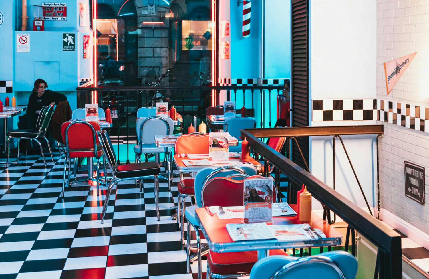 Retro diner with vibrant red, blue, and black furniture on a classic black-and-white checkered floor. 