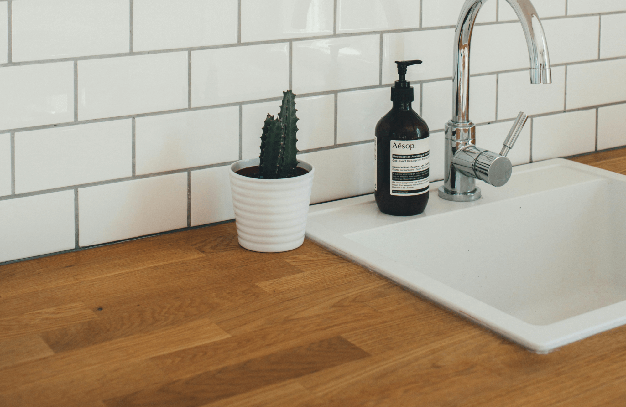 Crisp white subway tiles with contrasting grout provide a classic backsplash, enhancing the warmth of the natural wood countertop.