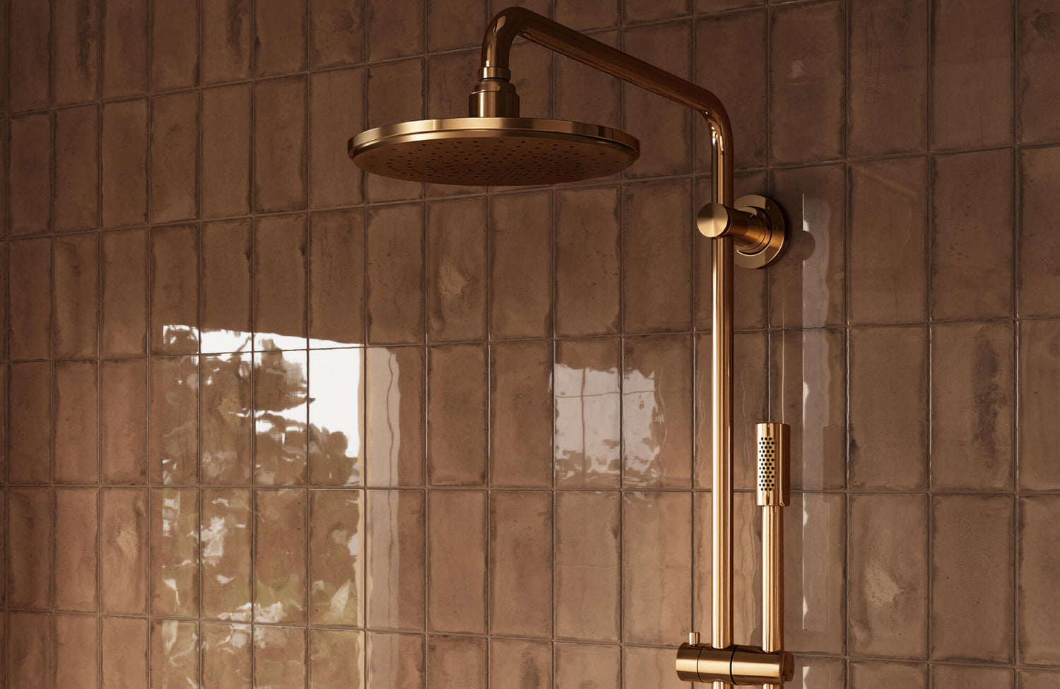 Warm-toned ceramic subway tiles with a glossy finish reflect natural light, creating a cozy yet elegant backdrop for the gold shower fixtures.