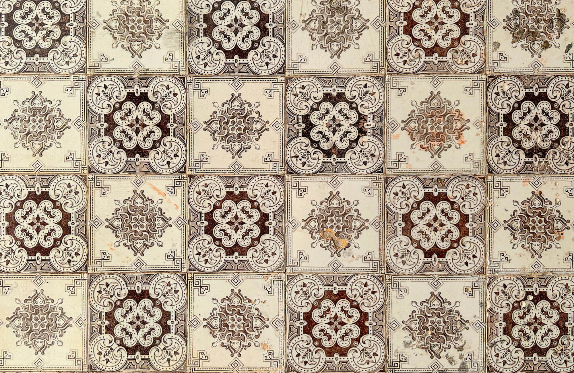 Intricate vintage tiles in a checkered layout featuring ornate floral and geometric patterns in muted browns and grays, perfect for adding a touch of classic elegance