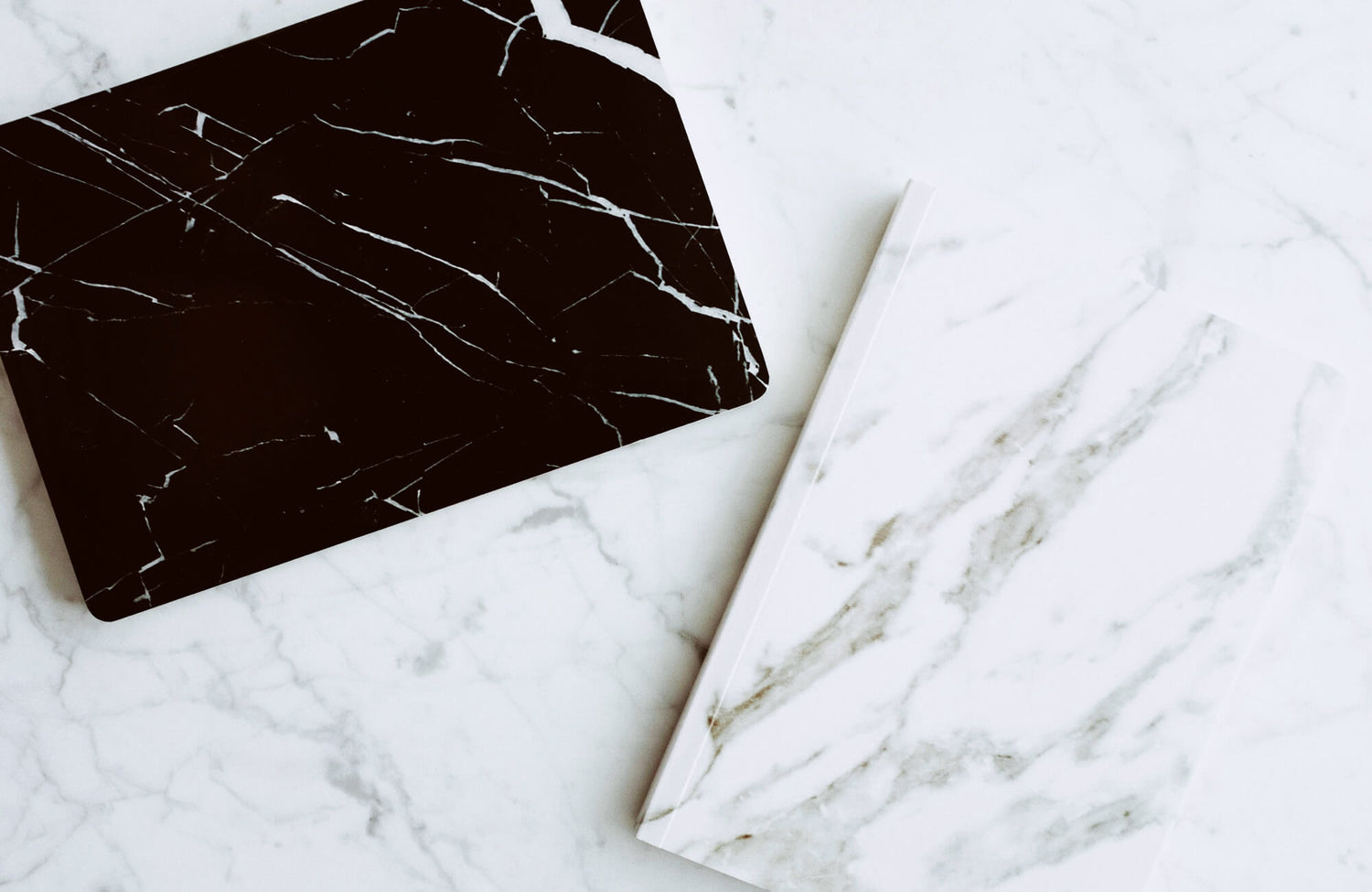 Black marble and white marble porcelain tile with distinctive veining patterns laid on a white marble background, highlighting the contrast between the two surfaces.