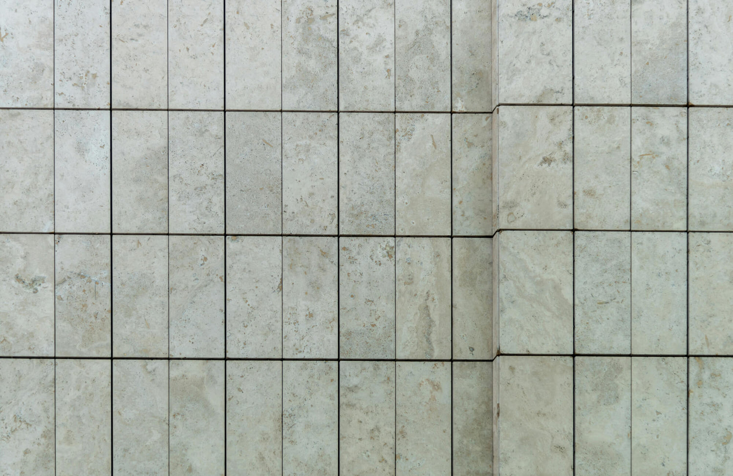 Close-up of cracked beige subway tiles with visible grout lines, highlighting texture and imperfections