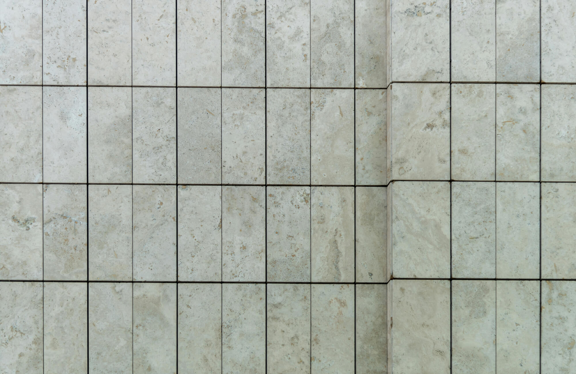 Close-up of cracked beige subway tiles with visible grout lines, highlighting texture and imperfections