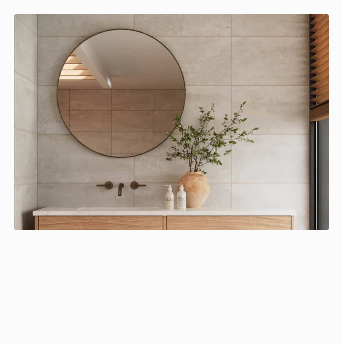 Serene bathroom vanity area featuring a round mirror, 12x24 neutral tiles, and warm wooden accents