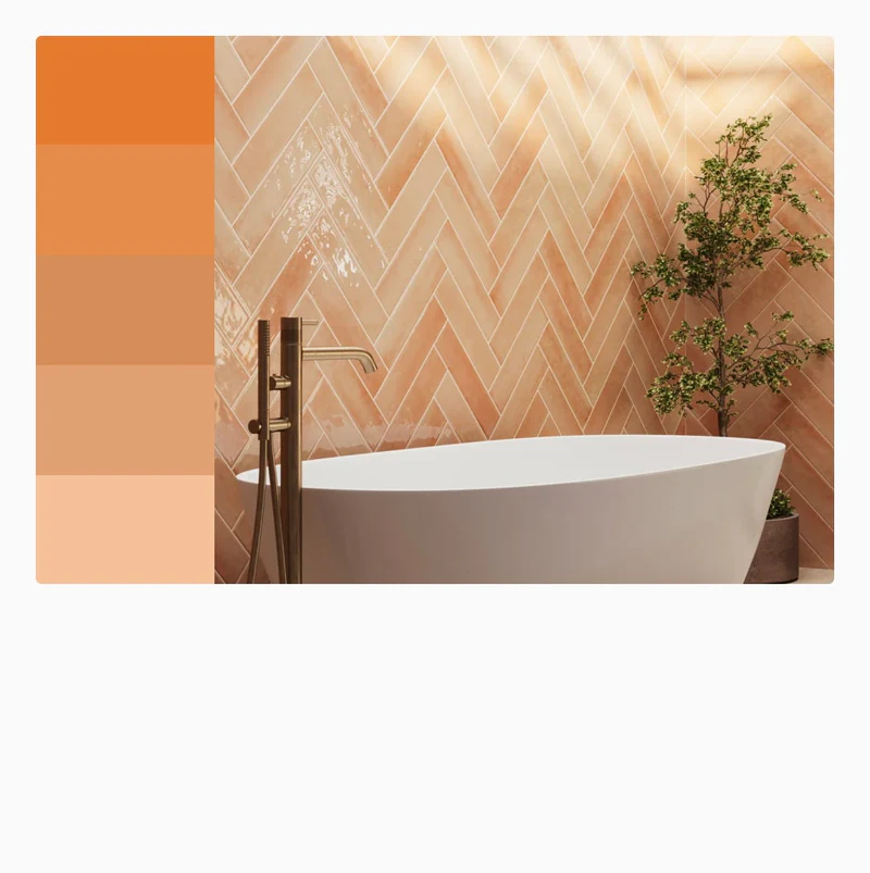 Vibrant orange herringbone tiles add warmth and energy to this bathroom, beautifully contrasting with the sleek white tub and gold fixtures