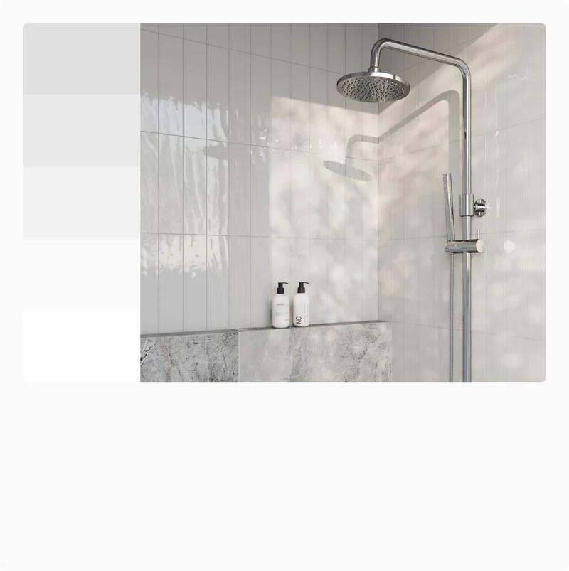 Glossy white tiles create a clean and refreshing shower space, paired with sleek chrome fixtures and a marble accent ledge