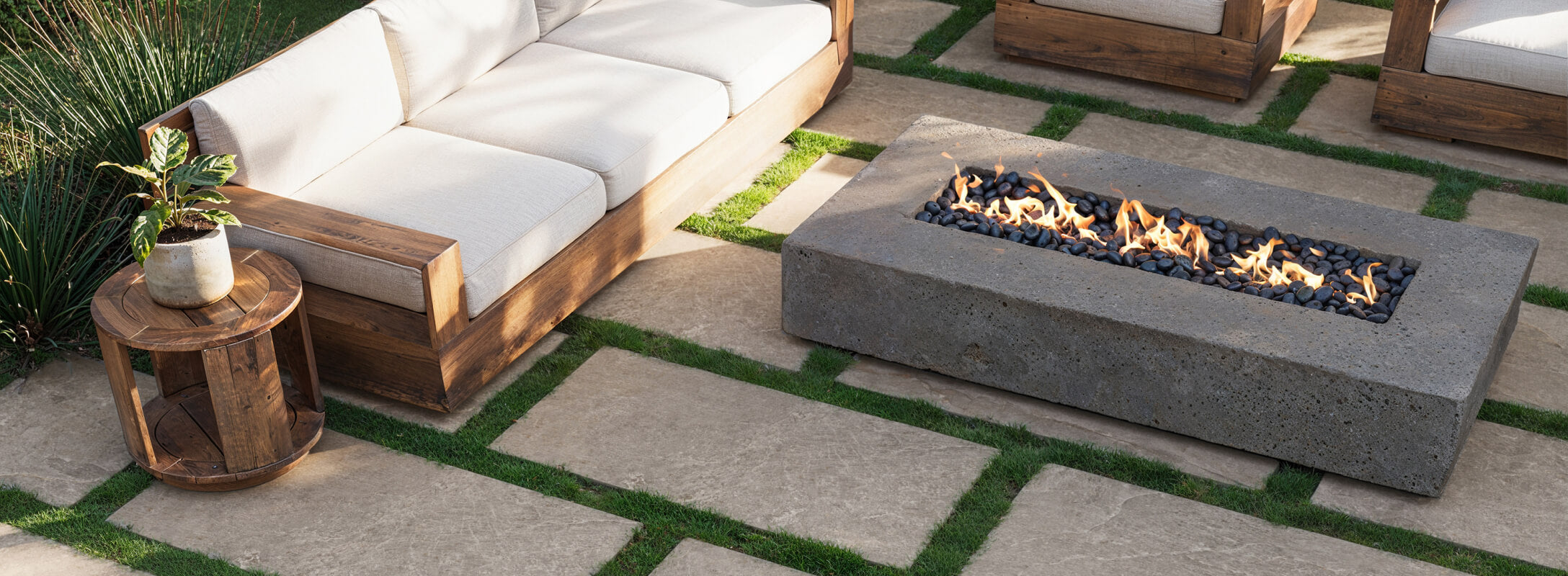 Modern outdoor patio featuring large format porcelain tiles that look like stone, complemented by a sleek fire pit and comfortable wooden seating