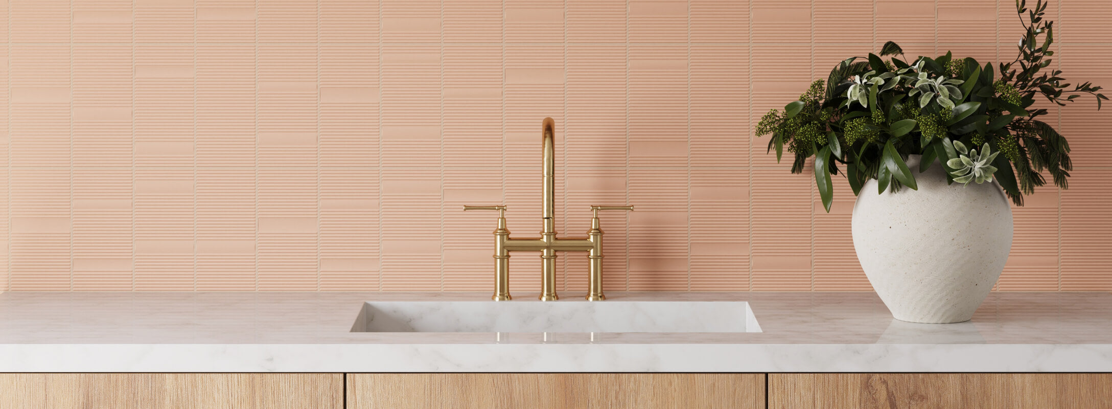 Modern kitchen with textured peach-orange backsplash tiles, a sleek brass faucet, and a white marble countertop accented by a vase of lush greenery