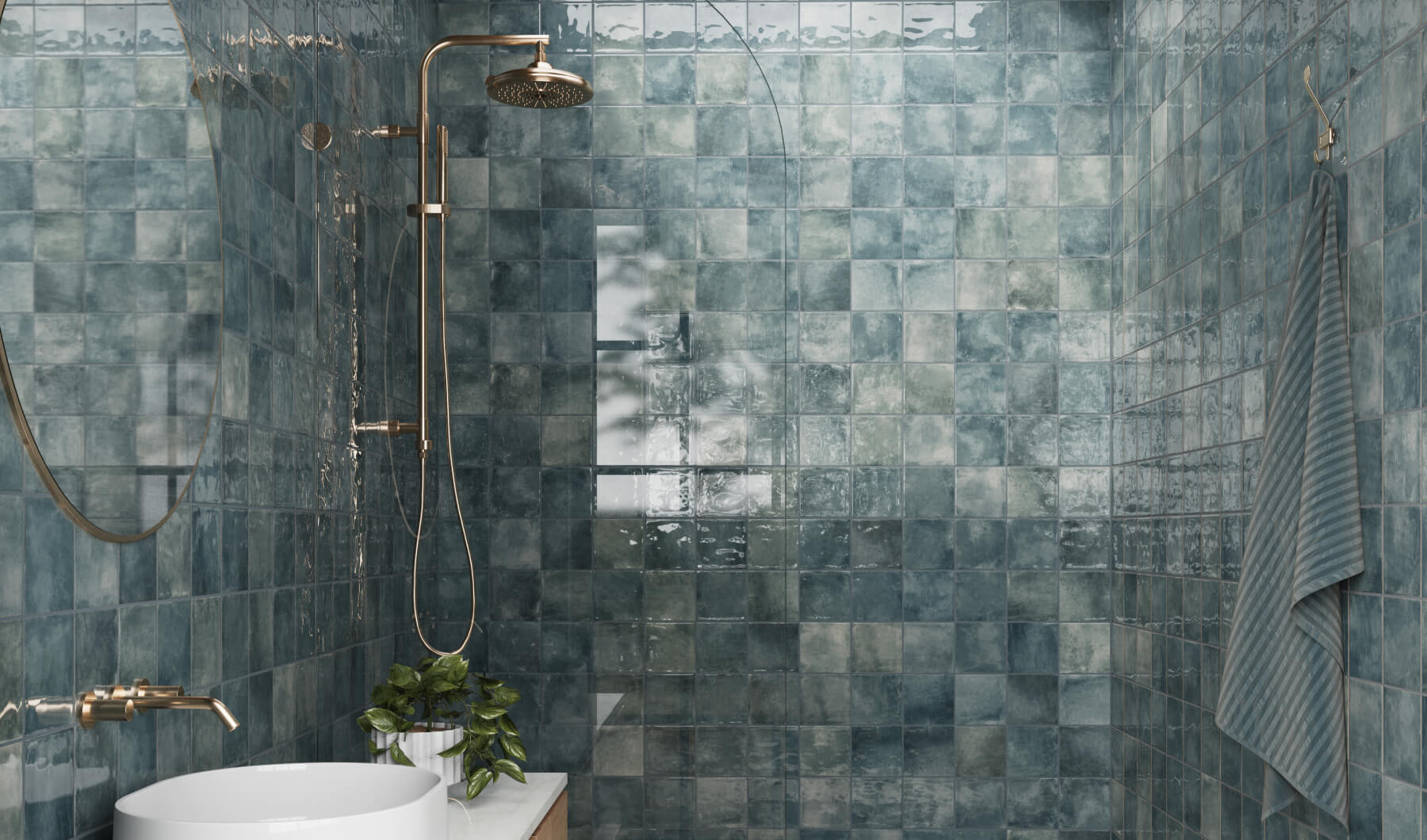 Chic shower adorned with glossy blue tiles, complemented by brass fixtures and lush greenery for a serene ambiance