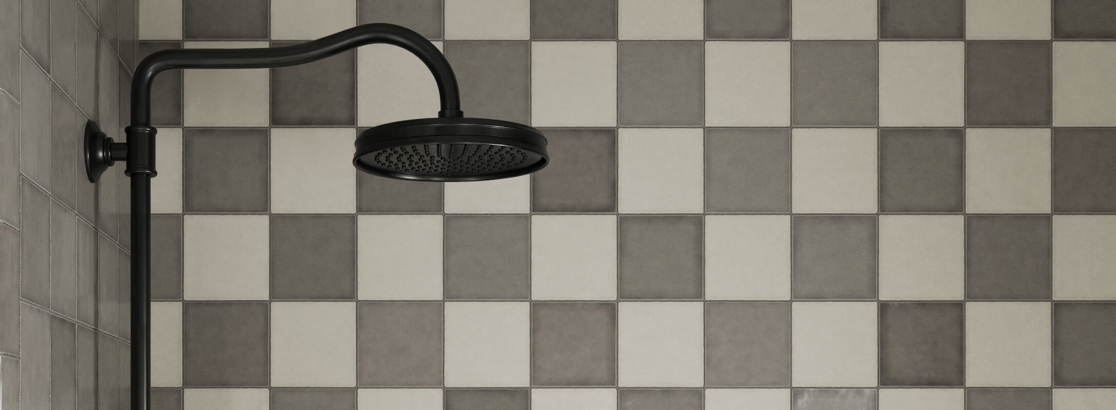 Modern shower with checkerboard tiles in shades of gray and beige, featuring a sleek black showerhead