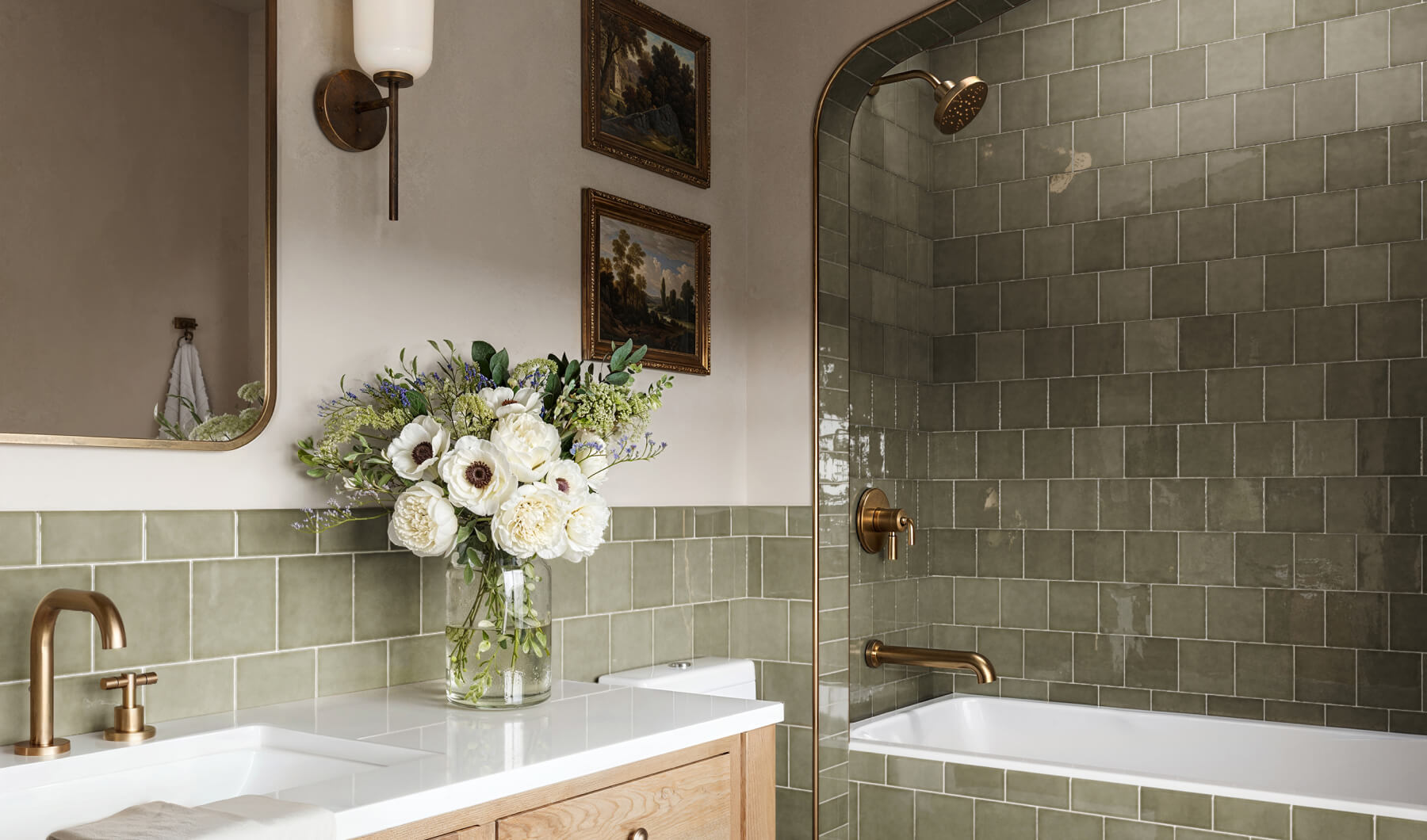 Elegant bathroom with olive green decorative tiles and brass fixtures, featuring a stylish vanity and a vase of fresh flowers