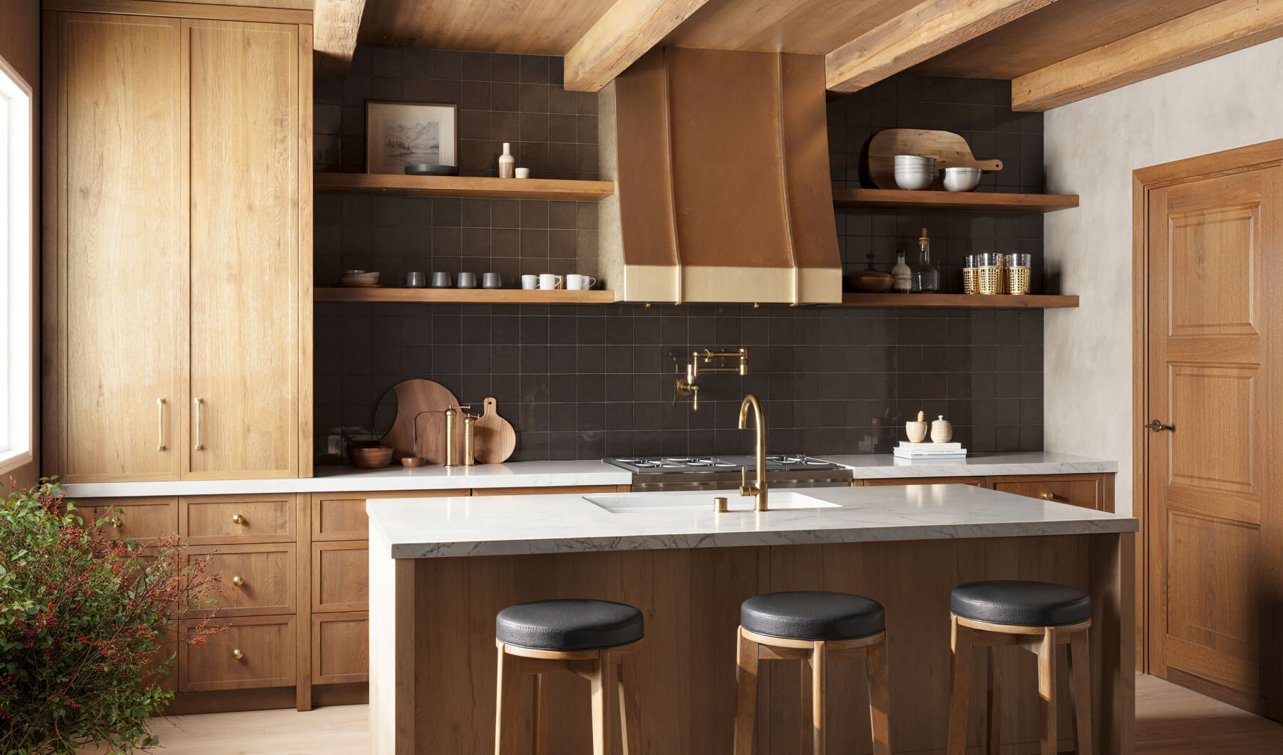 Warm rustic kitchen featuring decorative dark brown tiles, wooden cabinetry, open shelves, and a striking brass range hood for a modern farmhouse feel