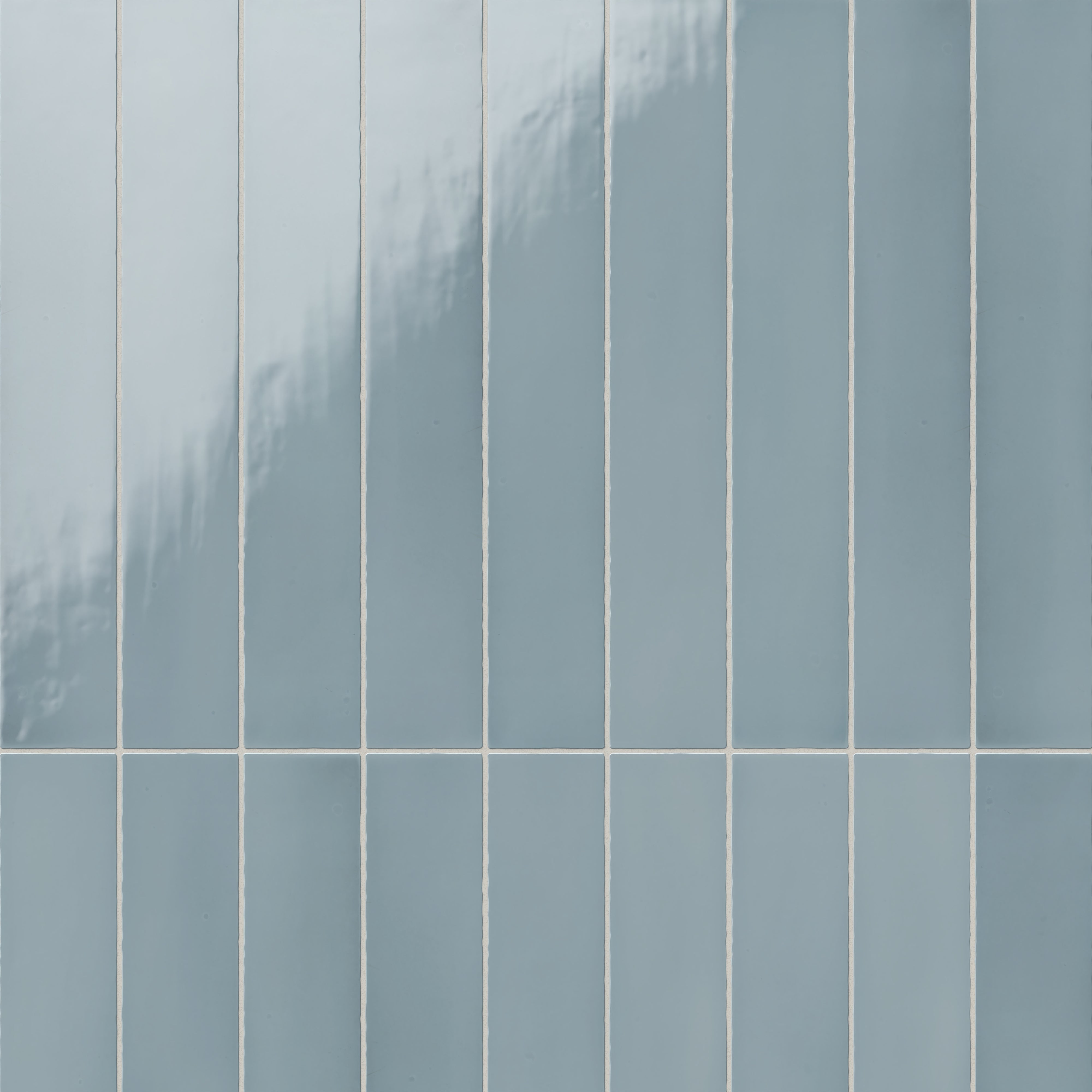 Vertical ceramic subway tiles with a subtle glossy surface, showcasing their smooth texture and soft, calming ocean blue hue