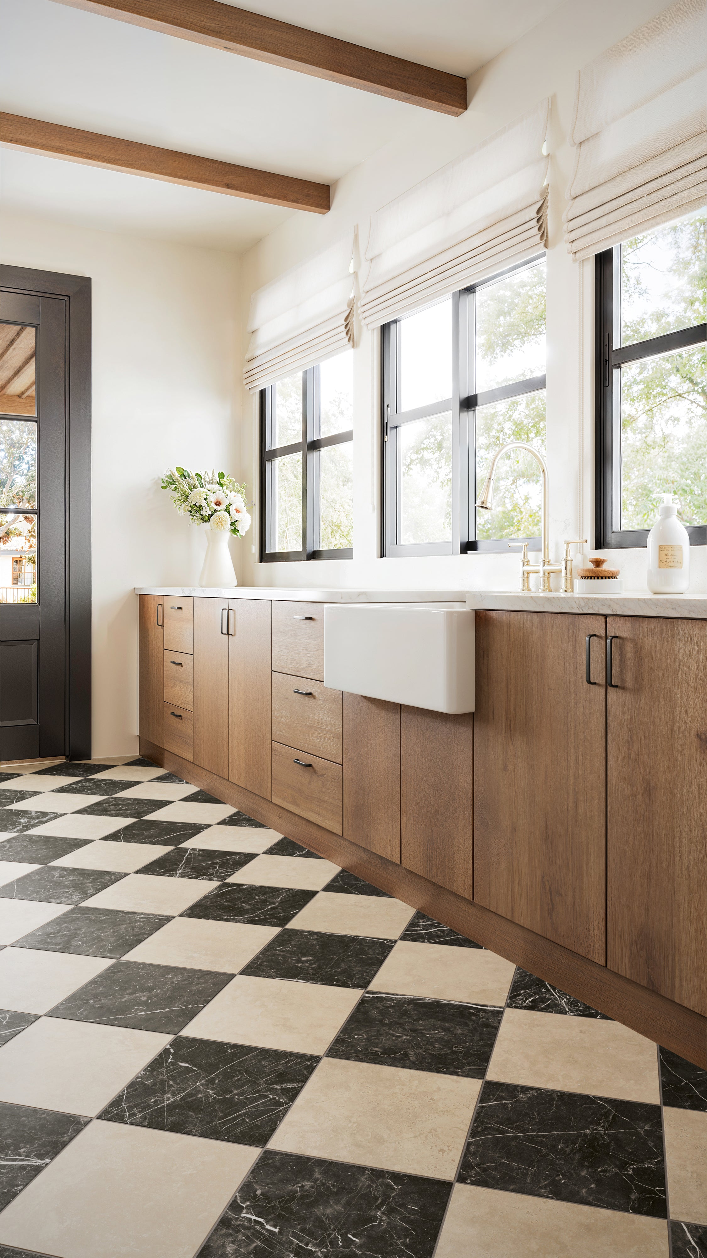 Leona Marfil and Nero Marquina Checkerboard 12x12 Matte tiles ground the kitchen, highlighting rustic wooden cabinets and expansive sunlit windows.