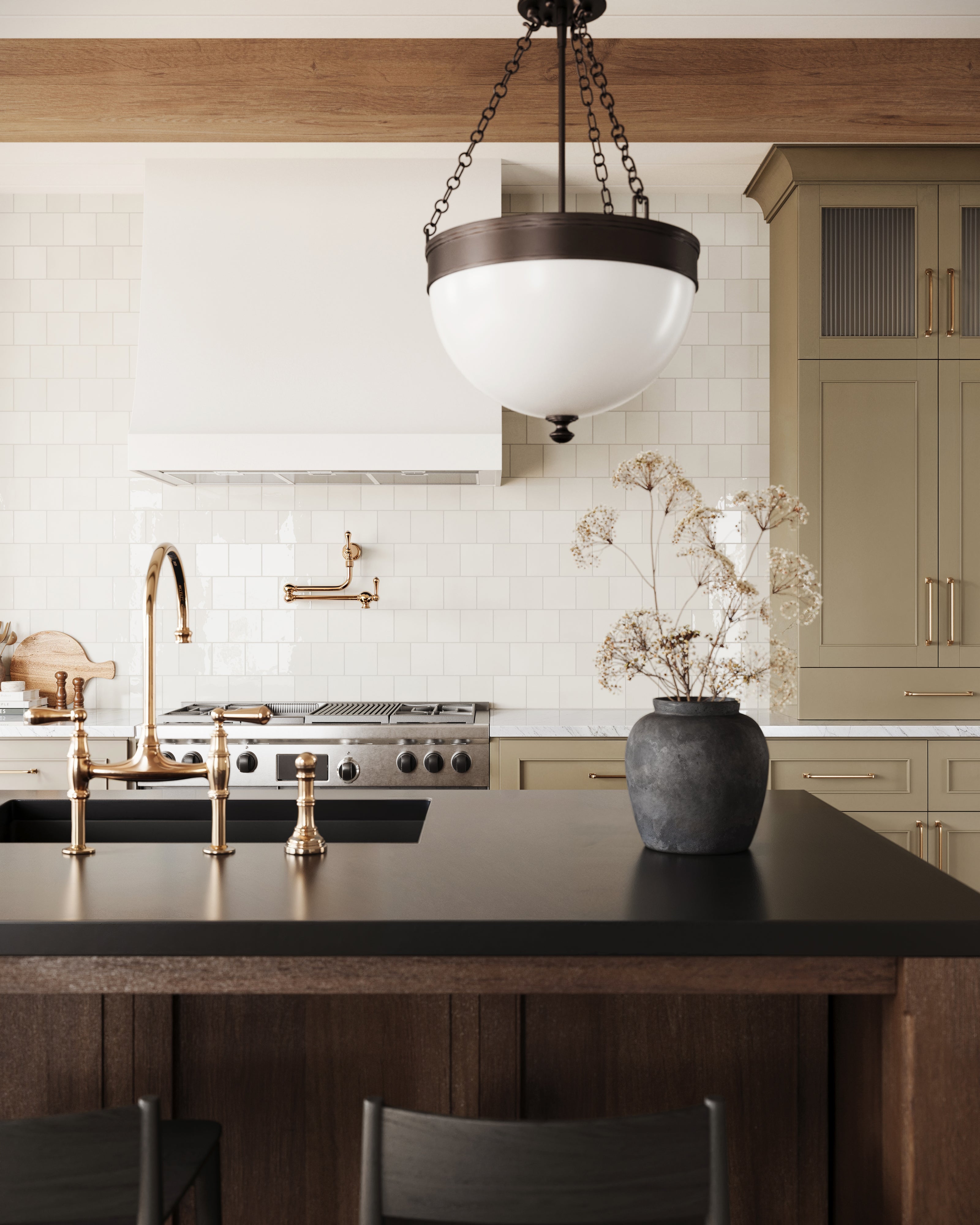 Close-up of a stylish kitchen with glossy white square tiles, brass fixtures, a black countertop, and olive green cabinetry